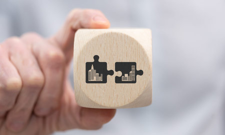 Hand holding a wooden cube with symbol of m&a concept