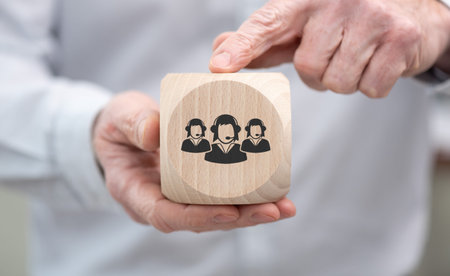 Hand holding a wooden cube with symbol of customer support concept