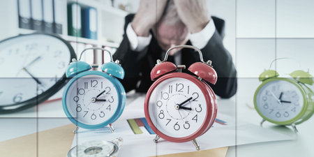 Stressed businessman behind his desk full of alarm clocks, geometric pattern