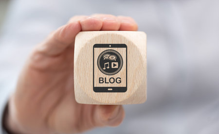 Hand holding a wooden cube with symbol of blog concept