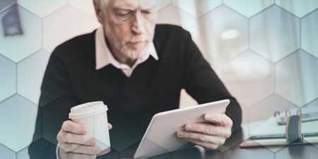 Senior businessman working on digital tablet at office, geometric patternの写真素材