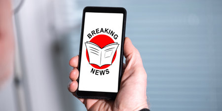 Hand holding a smartphone with breaking news conceptの写真素材