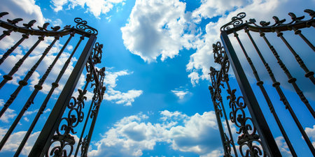 Elaborate iron gates opening wide under a bright blue sky filled with white clouds, symbolizing opportunity and freedomの素材