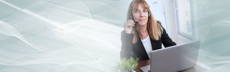 Mature businesswoman talking on a headset and using a laptop; panoramic banner