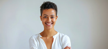 Portrait of a young woman with short hair smiling confidently, dressed casually against a plain backgroundの素材
