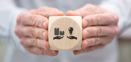 Hand holding a wooden cube with symbol of investors attraction conceptの写真素材