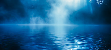 Serene scene of a misty blue lake with soft light rays filtering through, creating a tranquil atmosphere and gentle reflections on the water surfaceの素材