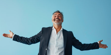 A cheerful mature man wearing a suit, smiling joyfully with arms open against a blue backgroundの素材