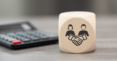 Wooden block with symbol of friendship concept and calculator on backgroundの写真素材