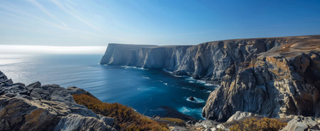 Expansive view of towering cliffs along a serene coastline with deep blue sea and clear skyの素材