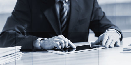 Businessman using a digital tablet in office, geometric patternの写真素材