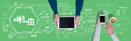 Top view of hands using digital tablet and mobile phone with symbol of government aid conceptの写真素材