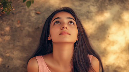 A young woman with long hair looks upwards thoughtfully against a textured backgroundの素材