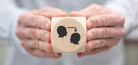 Hand holding a wooden cube with symbol of coaching concept
