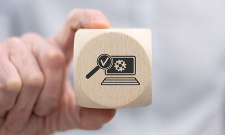 Hand holding a wooden cube with symbol of software testing conceptの写真素材