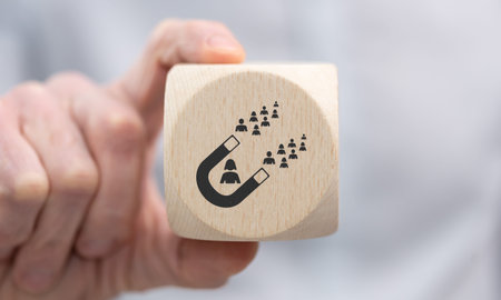 Hand holding a wooden cube with symbol of influence conceptの写真素材