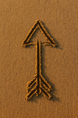 An arrow symbol crafted in sand, symbolizing direction and guidance on a beachの素材