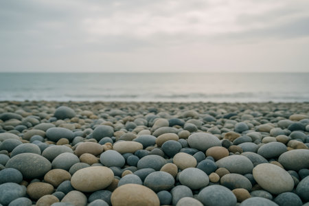 A collection of smooth pebbles lying on a tranquil beach near the oceanの素材