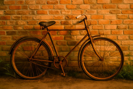 A vintage bicycle remains against a textured brick wall, illuminated by warm, soft lightingの素材
