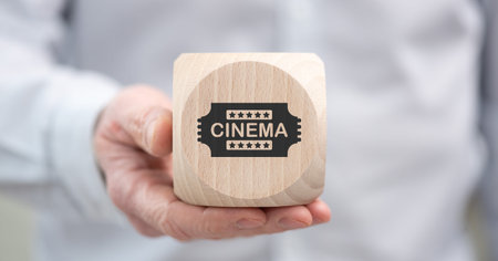 Hand holding a wooden cube with symbol of cinema conceptの写真素材