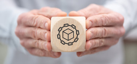 Hand holding a wooden cube with symbol of blockchain concept