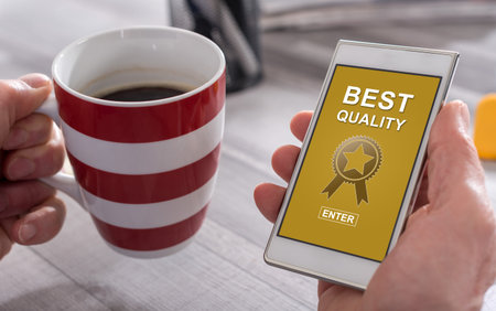 Male hand holding a smartphone with best quality conceptの写真素材