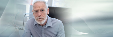 Portrait of senior businessman holding his glasses, looking at the camera; panoramic bannerの写真素材