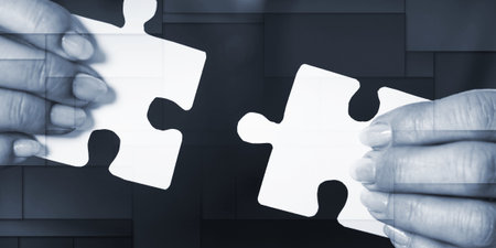 Hands joining two puzzle pieces, teamwork concept, geometric patternの写真素材