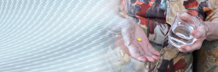 Senior holding a pill and a glass of water; panoramic bannerの写真素材