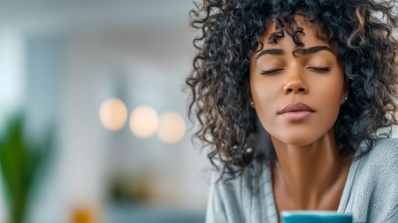 A young woman with curly hair enjoys a moment of tranquility with her coffeeの素材