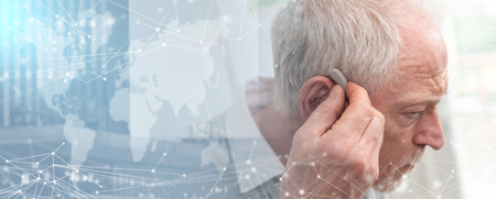 Senior man putting hearing aids; panoramic bannerの写真素材