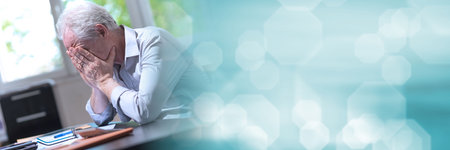 Stressed businessman sitting in office with head in hands; panoramic bannerの写真素材