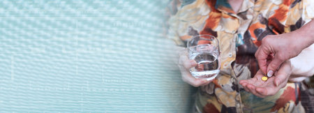 Hand giving a pill to an old woman; panoramic bannerの写真素材