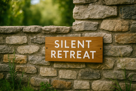A wooden sign reading silent retreat mounted on a stone wall amidst greeneryの素材
