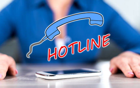 Smartphone with hotline concept between hands of a woman in backgroundの写真素材