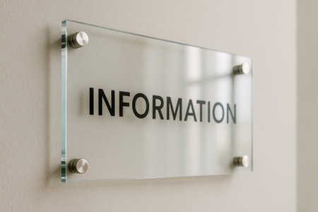 A sleek information sign mounted on a glass panel with metallic fixtures on a wallの素材
