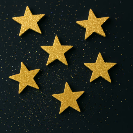 Glittery golden stars arranged on a black background, surrounded by scattered sparkles for decorationの素材