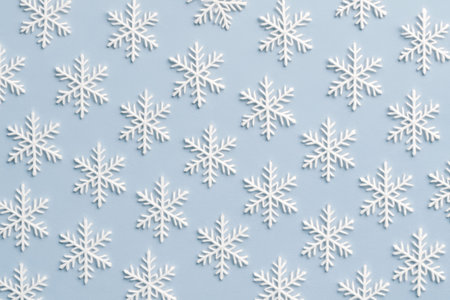 A repeating pattern of white snowflakes on a soft blue background creating a winter themeの素材