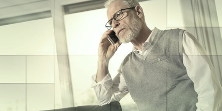 Portrait of senior businessman standing and talking on mobile phone in office, geometric pattern