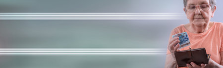 Old woman holding a banknote and her wallet; panoramic banner