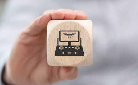 Hand holding a wooden cube with symbol of drone concept