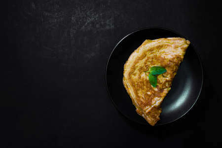 Picture of an appetizing yellow omelette on a black background There is space to put text. Street food, Image from the top viewの写真素材