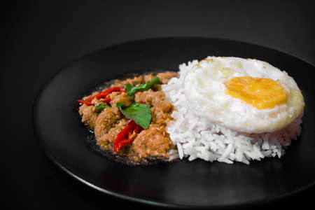 Rice with pork stir fried with basil and fried egg on black background, Thai food, Street food, Image from the top viewの写真素材