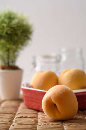 Yellow peaches fruit in a red bowl, Tropical juicy and sweet fruitの写真素材