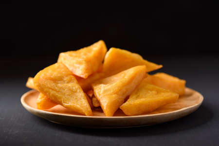 Deep fried Burmese tofu made from flour and chickpeas on black background
