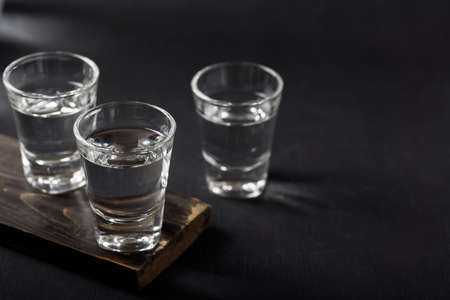 Vodka in a shot glass on black backgroundの写真素材