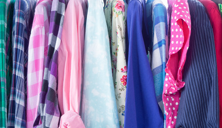 Multi-colored long-sleeved shirts hanging on a rack to sell on the cheap.の写真素材