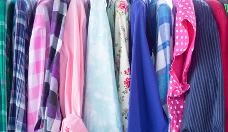 Multi-colored long-sleeved shirts hanging on a rack to sell on the cheap.の写真素材