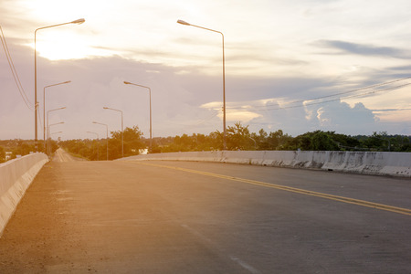 High-rise, two-lane road with sloping hills and horizon as the backdrop.の写真素材