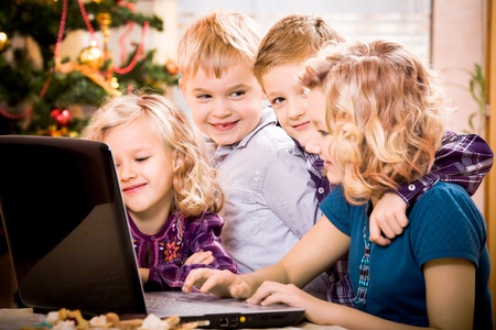 kids surfing with a laptop at the christmas treeの写真素材
